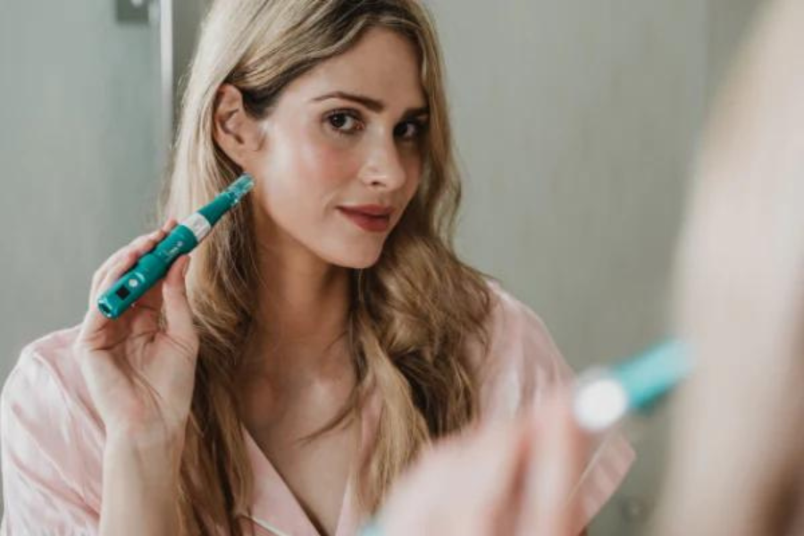 Woman holding  Dr Pen A6S Microneedling pen to her face